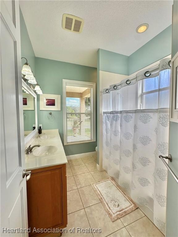 bathroom with a shower with curtain, tile patterned flooring, vanity, and a textured ceiling