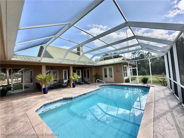 view of swimming pool featuring glass enclosure, french doors, and a patio