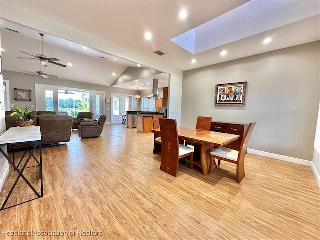 dining area with light hardwood / wood-style floors, vaulted ceiling, and ceiling fan