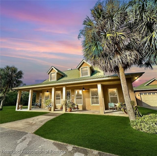 back house at dusk featuring a yard and covered porch