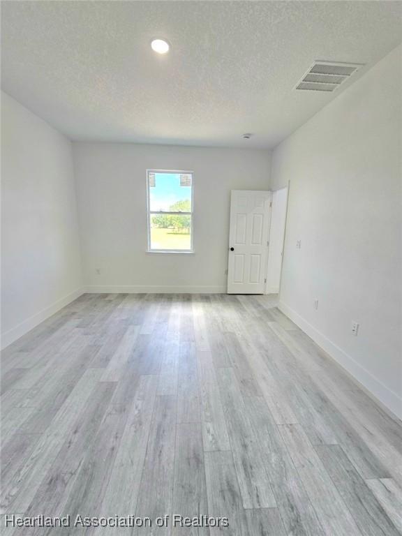 425 Floral Dr, Sebring, FL 33876 - unfurnished room featuring light wood-style floors, a textured ceiling, baseboards, and recessed lighting