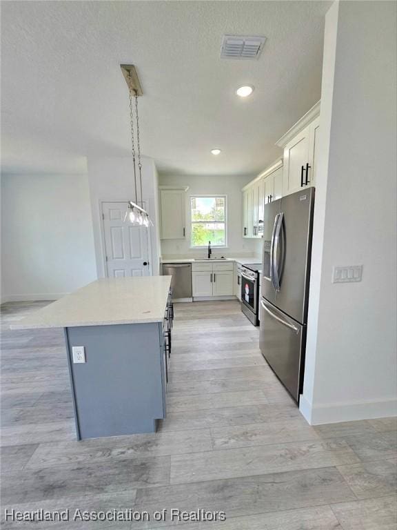425 Floral Dr, Sebring, FL 33876 - kitchen with stainless steel appliances, baseboards, a kitchen island, light wood-style flooring, and recessed lighting