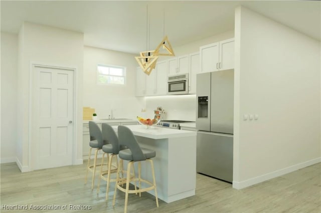 kitchen featuring a breakfast bar, white cabinetry, hanging light fixtures, stainless steel fridge, and a kitchen island