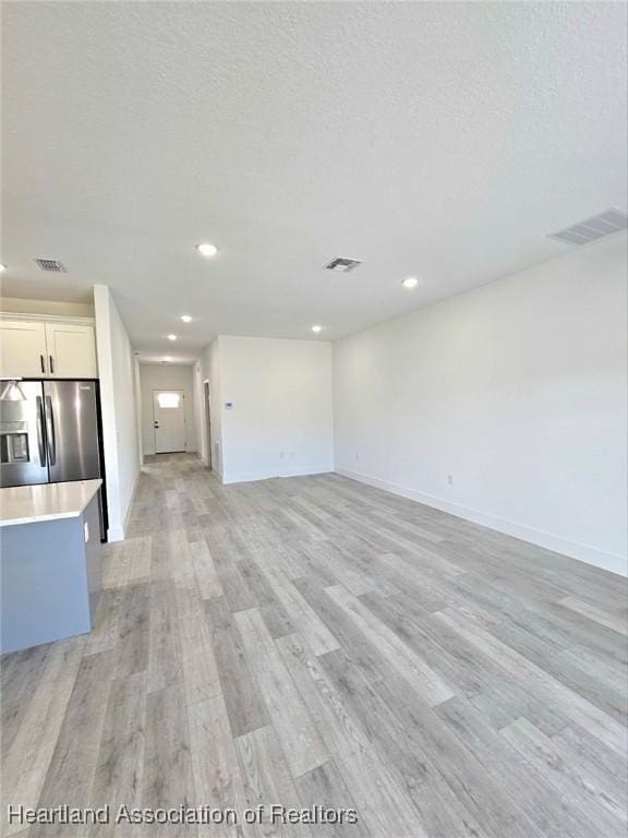 425 Floral Dr, Sebring, FL 33876 - unfurnished living room with light wood finished floors, recessed lighting, and baseboards