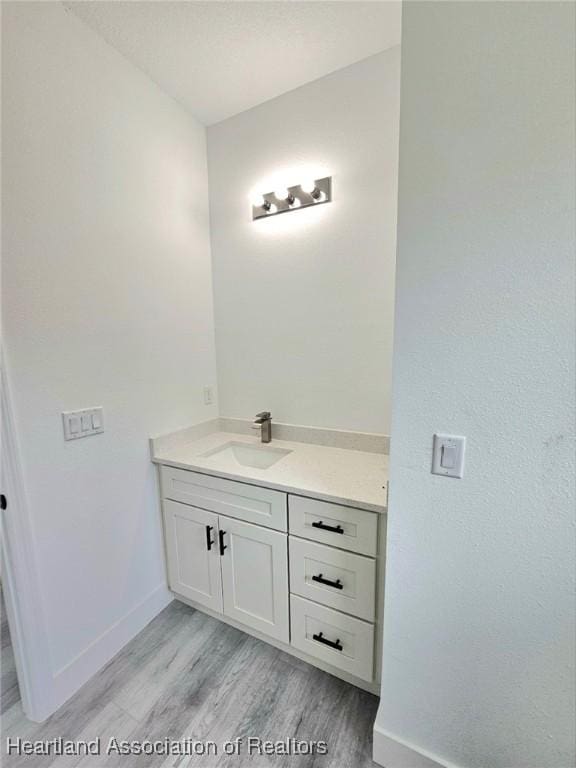 425 Floral Dr, Sebring, FL 33876 - bathroom with vanity, wood finished floors, and baseboards