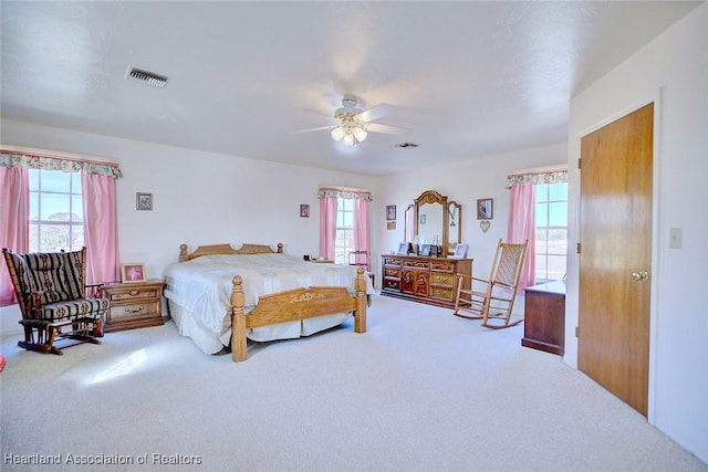 carpeted bedroom featuring multiple windows and ceiling fan