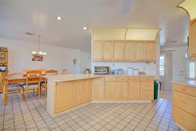 kitchen with light brown cabinets, hanging light fixtures, light tile patterned floors, a notable chandelier, and kitchen peninsula