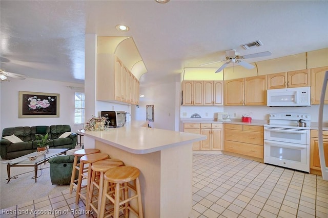 kitchen with a breakfast bar, white appliances, light brown cabinetry, light tile patterned flooring, and kitchen peninsula