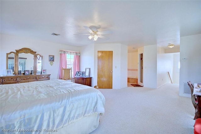 carpeted bedroom with ensuite bathroom and ceiling fan