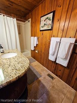 bathroom with wood walls, sink, and wood ceiling