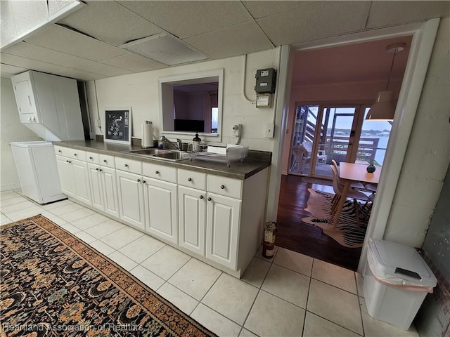 kitchen featuring sink, white cabinets, light tile patterned floors, and independent washer and dryer