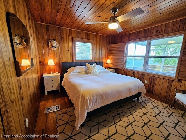 bedroom with ceiling fan, wooden ceiling, and wooden walls