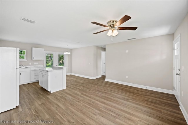 kitchen featuring pendant lighting, white cabinets, ceiling fan with notable chandelier, a kitchen island, and white fridge