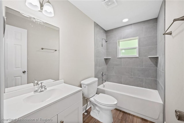 full bathroom featuring hardwood / wood-style floors, vanity, toilet, and tiled shower / bath