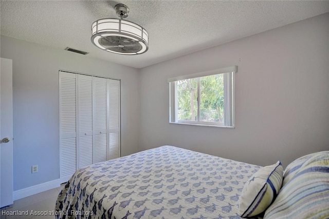 bedroom featuring a textured ceiling, a closet, visible vents, and baseboards