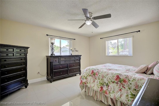 bedroom with multiple windows, a ceiling fan, and a textured ceiling