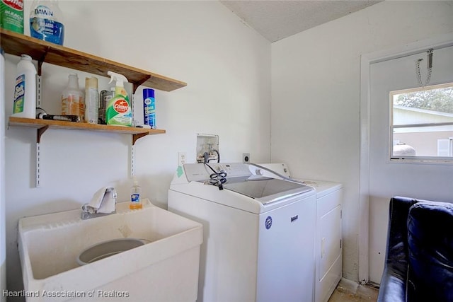 clothes washing area featuring laundry area, a sink, a textured ceiling, and washing machine and clothes dryer