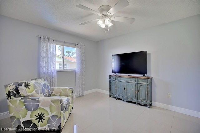 living room with a textured ceiling, light tile patterned floors, a ceiling fan, and baseboards