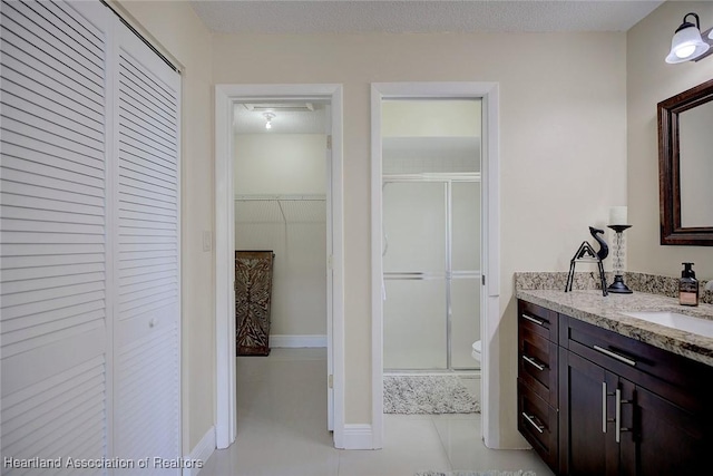 full bathroom with toilet, a stall shower, tile patterned floors, and vanity