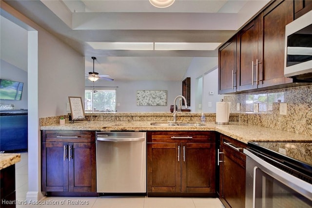 kitchen with decorative backsplash, lofted ceiling, light stone counters, stainless steel appliances, and a sink