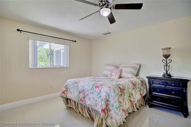 tiled bedroom featuring a ceiling fan, visible vents, baseboards, and a textured ceiling