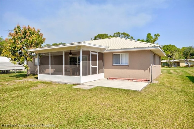 rear view of property featuring a lawn, a patio, a sunroom, metal roof, and stucco siding