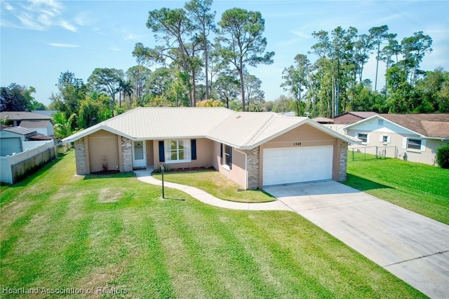 ranch-style house with concrete driveway, metal roof, an attached garage, fence, and a front lawn