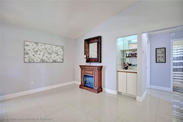 unfurnished living room featuring lofted ceiling, light tile patterned floors, a textured ceiling, and a glass covered fireplace