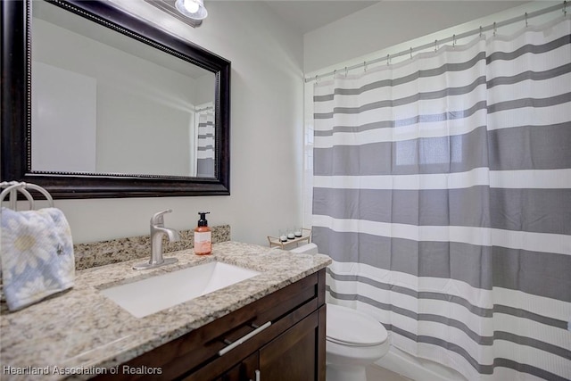 full bath with curtained shower, vanity, and toilet