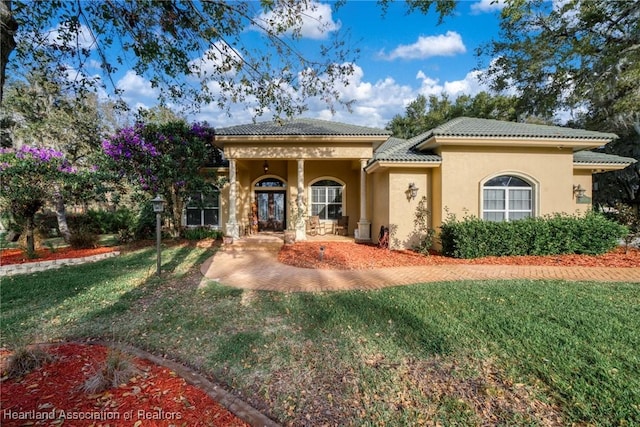 mediterranean / spanish house with a tile roof, a front lawn, and stucco siding