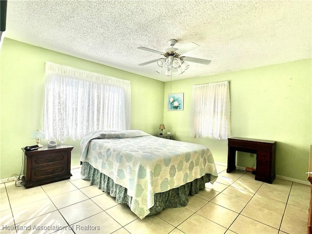 bedroom featuring ceiling fan, light tile patterned floors, and a textured ceiling