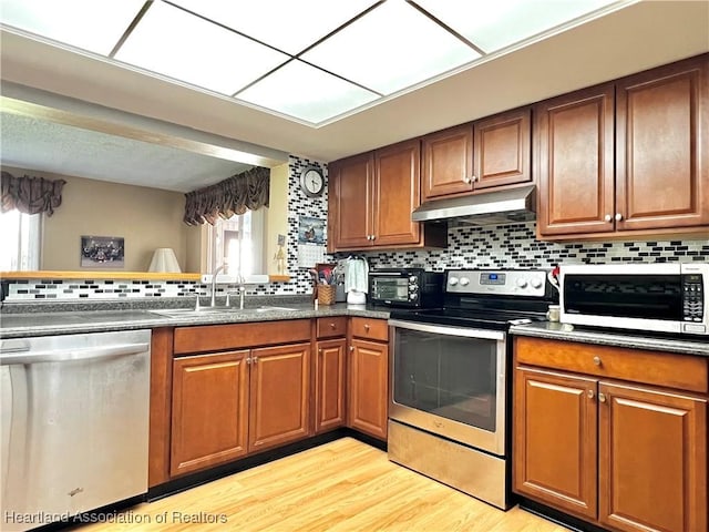 kitchen with stainless steel appliances, light hardwood / wood-style flooring, tasteful backsplash, and sink