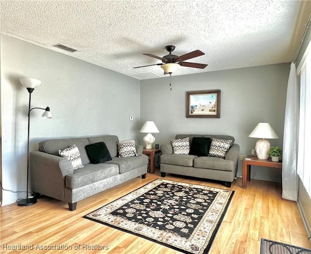 living room featuring wood-type flooring, a textured ceiling, and ceiling fan