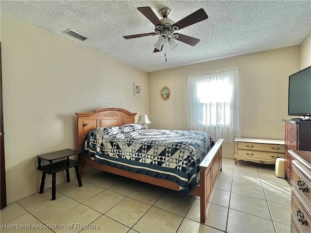 bedroom with ceiling fan, light tile patterned floors, and a textured ceiling