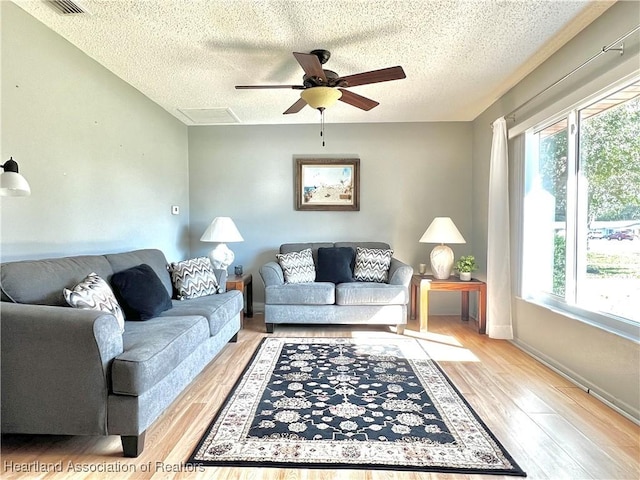 living room with a textured ceiling, ceiling fan, light hardwood / wood-style flooring, and plenty of natural light