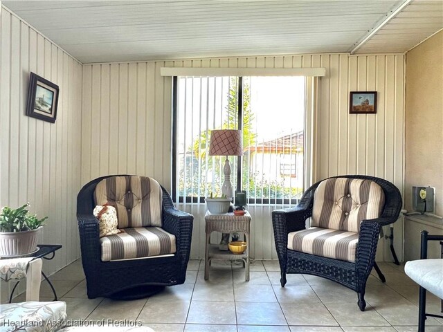 sitting room with wood walls and light tile patterned flooring