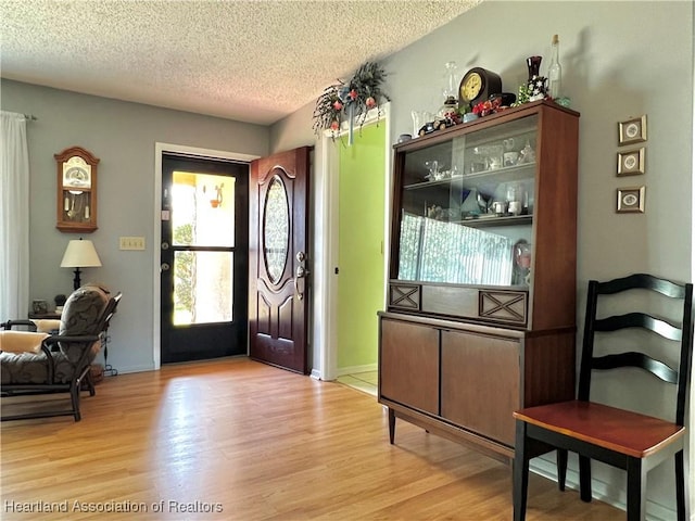 entryway with light wood-type flooring and a textured ceiling