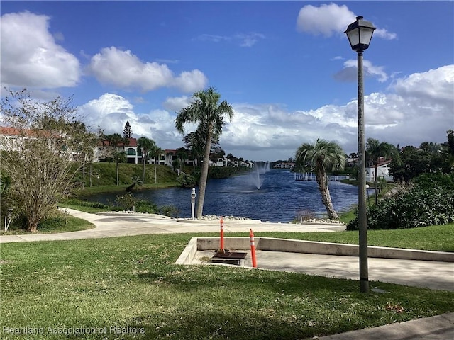 view of property's community with a water view and a lawn