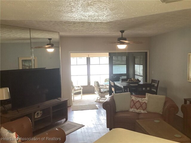 living room featuring ceiling fan, a textured ceiling, and hardwood / wood-style flooring