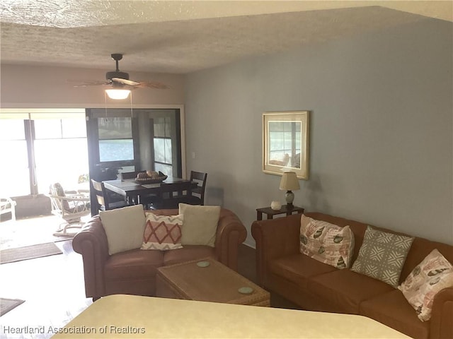 living room featuring ceiling fan and a textured ceiling