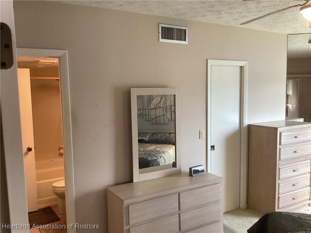 bedroom featuring a textured ceiling, ensuite bath, and ceiling fan