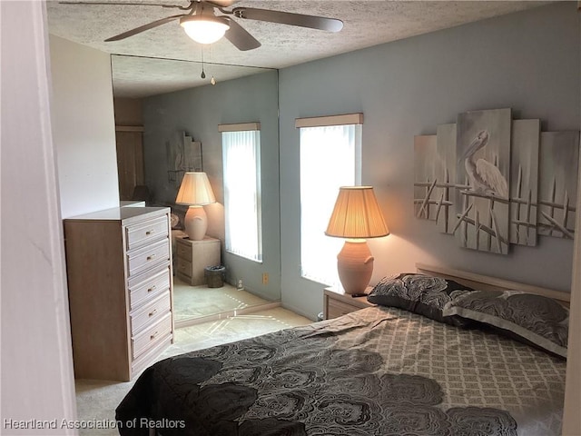 bedroom with light carpet, a textured ceiling, and ceiling fan