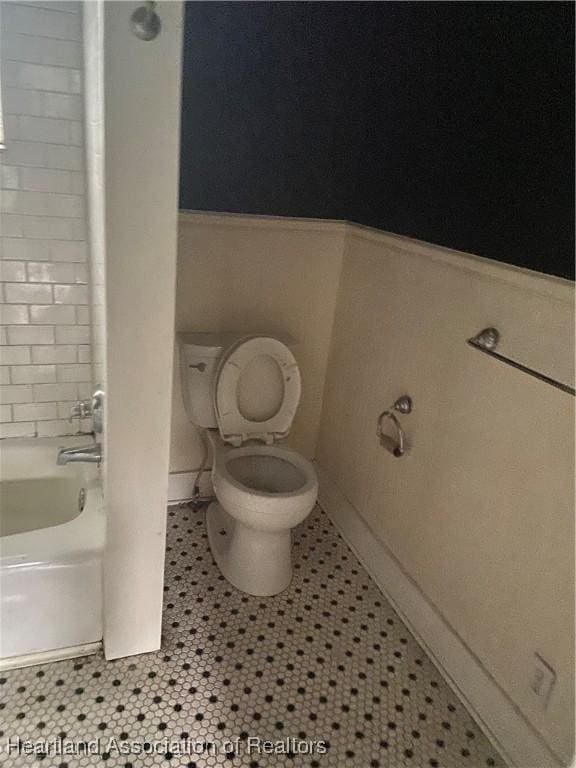 bathroom featuring tile patterned floors, a washtub, and toilet