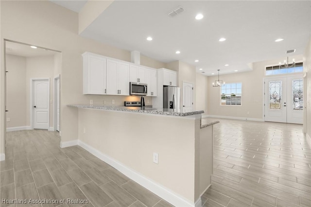 4825 Whiting Dr, Sebring, FL 33870 - kitchen featuring a notable chandelier, white cabinetry, visible vents, wood finish floors, and appliances with stainless steel finishes