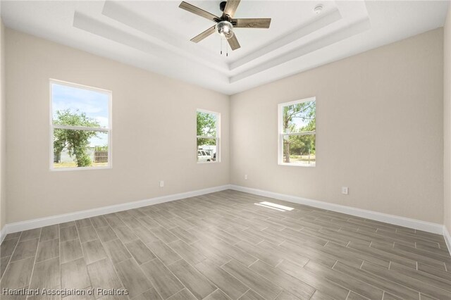 4825 Whiting Dr, Sebring, FL 33870 - empty room featuring a tray ceiling, ceiling fan, baseboards, and wood finished floors