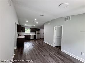 unfurnished living room featuring dark wood-type flooring, visible vents, baseboards, and recessed lighting