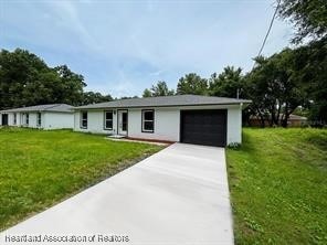 ranch-style house featuring an attached garage, driveway, and a front yard