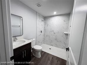 full bath featuring a shower stall, wood finished floors, vanity, toilet, and visible vents