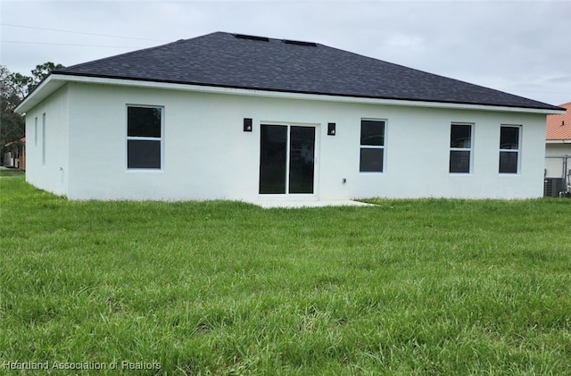 rear view of property featuring a lawn and central AC