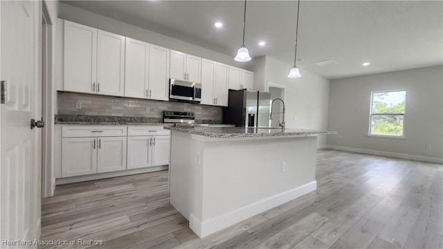 kitchen with white cabinets, stainless steel appliances, and a kitchen island with sink